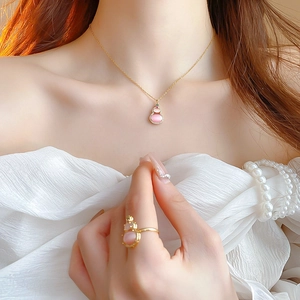 Detailed close-up of pink cat eye stone gourd necklace and ring set in gold plating