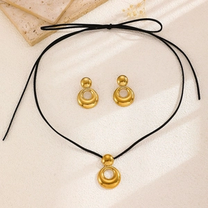 Close-up of golden teardrop pendant necklace and stud earrings set on a marble coaster