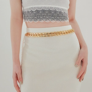 Detail of chunky golden acrylic chain belt with adjustable link on white dress