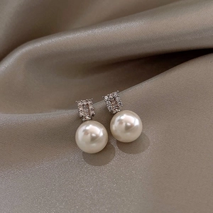 Macro shot of silver pearl tassel earring on silk fabric showing detailed diamond inlay