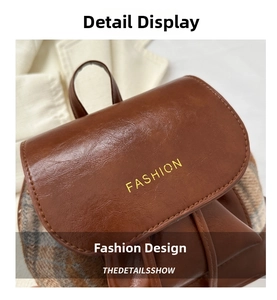 Detailaufnahme brauner Lederrucksack mit Karostoff-Einsätzen und Fashion-Schriftzug-Verzierung