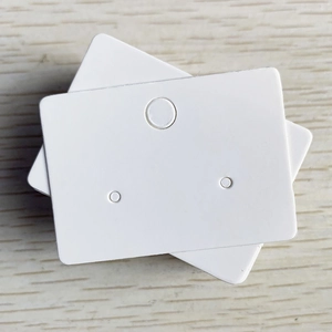 White rectangular earring display cards with three-hole design on wood background