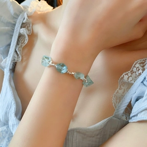 Dettaglio del bracciale con pietre azzurre irregolari e perline d'argento sul polso