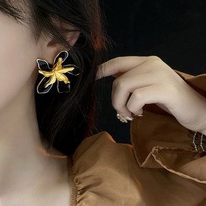 Close-up of vintage layered flower earrings with gold and black enamel finish on model