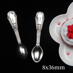 Miniature silver dollhouse spoons measuring 8x36mm shown with a tiny cake model