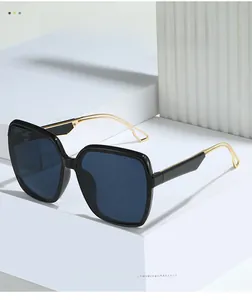 Detail of square oversized sunglasses with gold hollow geometric temples on white stone