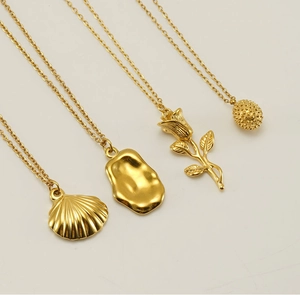 Detail of four gold necklaces featuring rose flower, shell, and lava pendants