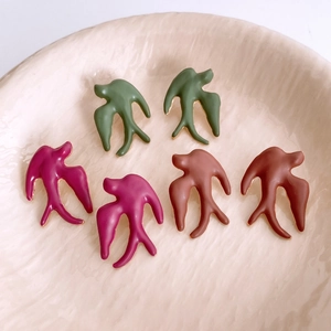 Macro detail of painted swallow bird pendants in dark green, purple, and brown colors