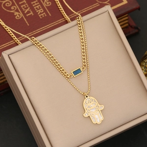 Detail der doppelstöckigen Goldhalskette mit blauem Edelstein und Hamsa-Hand-Anhänger