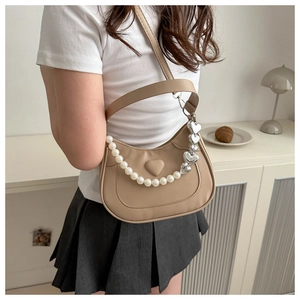 Detail of khaki crescent moon bag featuring a heart-shaped relief and pearl handle charm