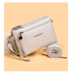 Detail view of beige multi-compartment PU leather crossbody bag with metal zippers