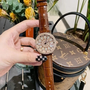 Detail of a rose gold watch with a spinning flower dial and crystal-studded bezel
