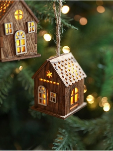 Dettaglio di casetta di Natale in legno a LED appesa all'albero con luce calda bokeh