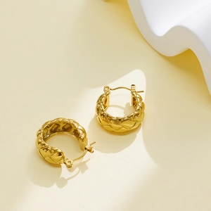 Macro detail of gold-plated braided hoop earrings featuring a diamond-patterned relief