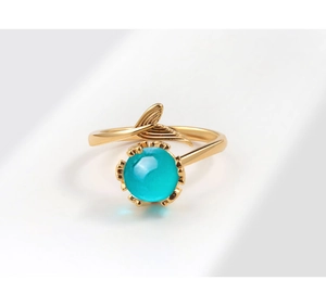 Detail of gold-plated mermaid tail ring with a turquoise round gemstone in close-up view