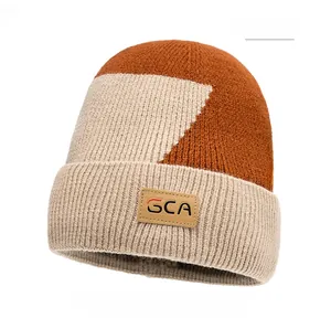 Dettaglio del berretto in maglia bicolore arancione e kaki con etichetta in pelle GCA