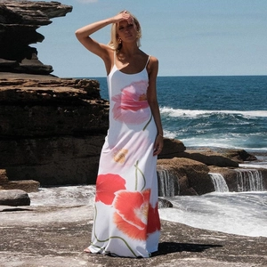 Detail of vibrant pink floral print on a white summer maxi dress with sea background