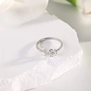 Detail of silver clover and butterfly ring with marquise zircon on a textured stone