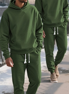 Detail view of dark green jacquard knit tracksuit with textured hoodie and joggers on model