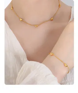 Detail of heart pendants on thin gold chain necklace and matching bracelet set