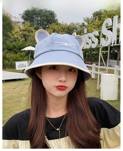 Close-up of light blue sun hat with cat ear accents and delicate facial embroidery