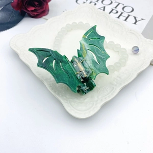 Green marble pattern acetate hair claw clip with stylish bat wing design on white plate