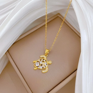 Detail view of a hollow turtle pendant necklace with gold plating and sparkling crystals