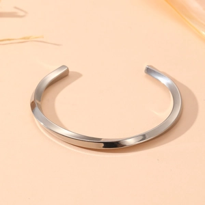 Detailed view of silver stainless steel bangle with elegant twisted design and glossy finish