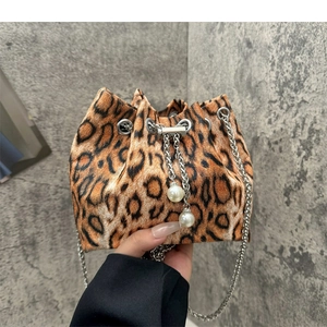 Leopard print bucket bag with silver chain and pearl charms held against a wall