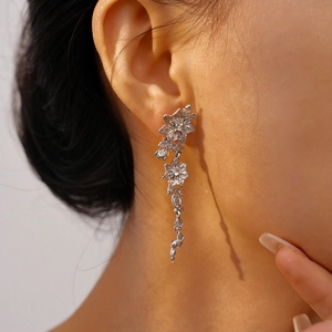 Close-up of layered silver flower drop earrings showing delicate texture and fit