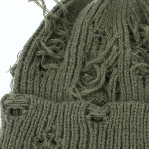 Macro shot of army green distressed knit beanie showing ripped holes and frayed texture