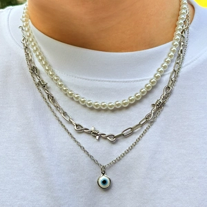 Three-layer layered necklace featuring white pearls, silver thorn chain, and blue evil eye pendant