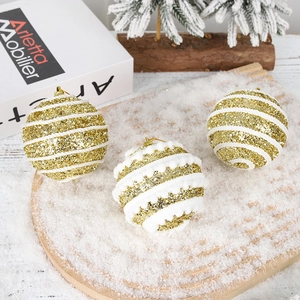 Close-up of three gold glitter Christmas balls with stripes on a snowy wooden tray