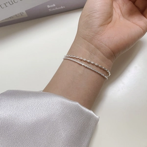 Close-up of a double-layered 925 sterling silver bracelet on a wrist with shimmering beads