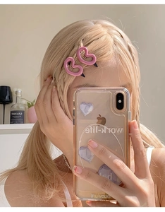 Détail de pinces à cheveux roses en forme de cœur évidé sur une coiffure tressée blonde