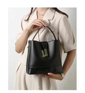 Detail of black pebbled and croc-embossed leather bucket bag with gold metal buckle