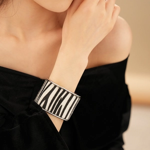 Detail of zebra print velvet cuff bracelet with silver edges worn by a model