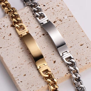 Polished gold and silver Cuban chain bracelets with ID bars on neutral stone background