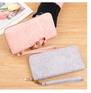 Close-up of pink and grey zip-around long wallets with embossed floral patterns