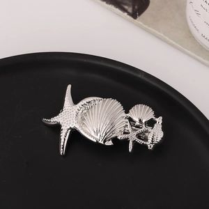 Detailed close-up of starfish and seashell alloy hair clips on a black matte plate
