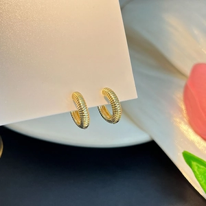 Détail de boucles d'oreilles créoles dorées en forme de cœur avec perles sur carte blanche
