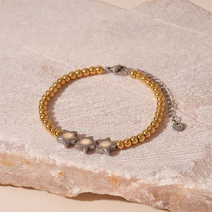 Gros plan du bracelet perlé avec pendentif étoile sur pierre montrant les détails fins