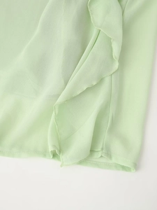 Detail of light green chiffon dress showing ruffle trim and fine stitching on the hemline