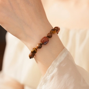 Détail du bracelet en perles d'œil de tigre et bois d'agar sur le poignet