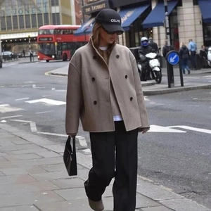 Elegant beige double-breasted wool coat with a stand-up collar for women in city street