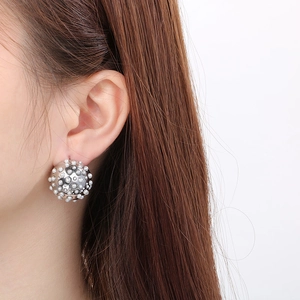 Detailed close-up of a silver semi-sphere earring studded with white pearls on a model