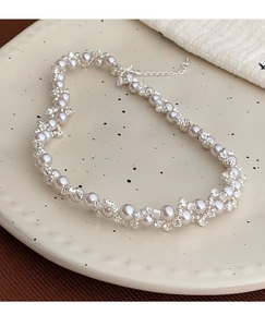 Detailed close-up of alternating woven pearls and crystal beads on a flower-shaped necklace