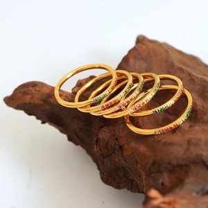 Set of seven minimalist gold stacking rings featuring colorful zircon stones on wood