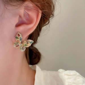 Detail of colorful zircon butterfly earring worn on ear with elegant gold finish