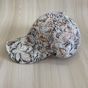Détail de casquette de baseball blanche avec motifs de feuilles et détails bronzes